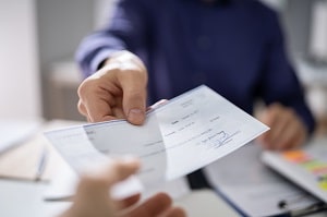 man in suit handing over a paper to another man | question to ask pressure washing company