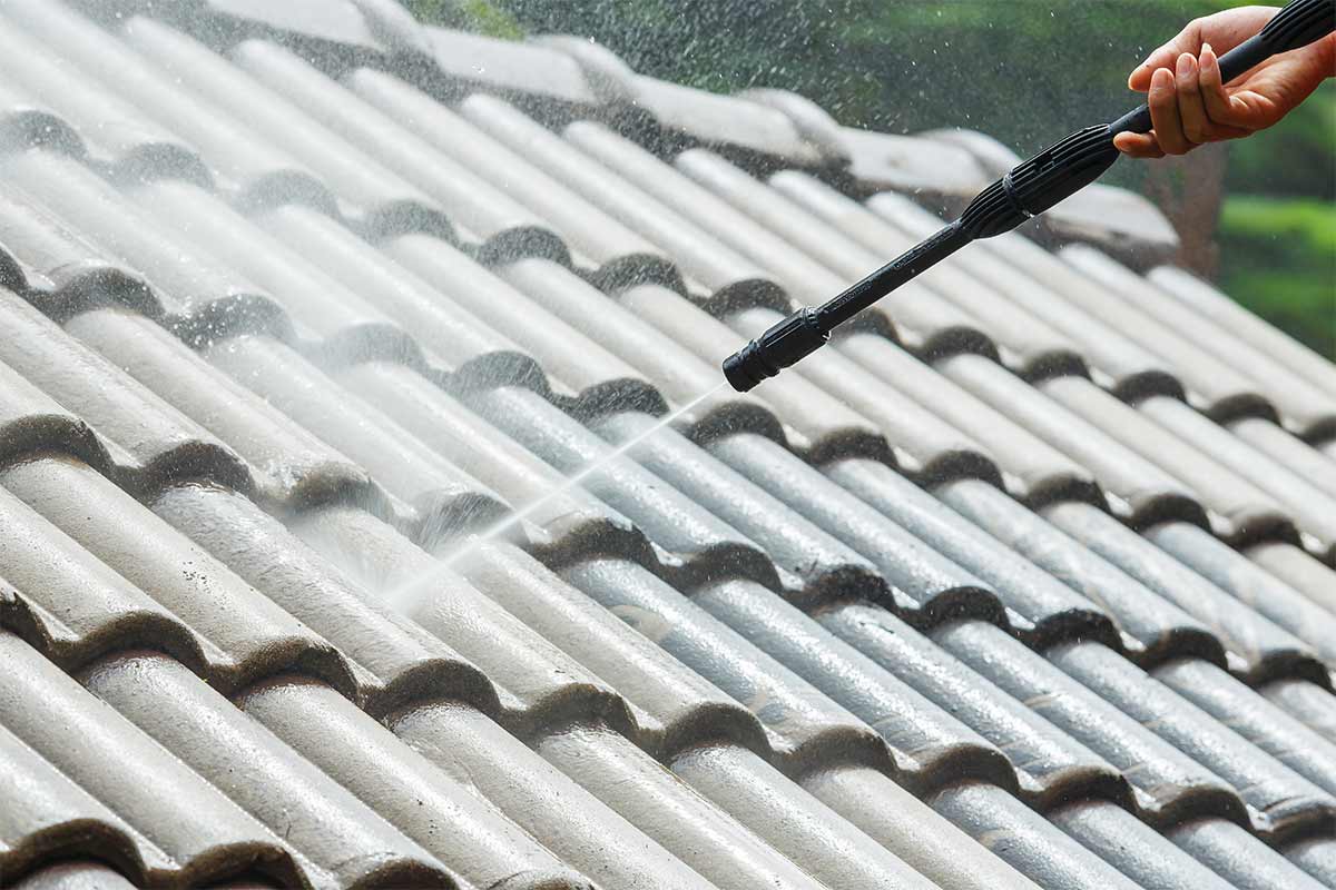 Roofing contractor using a pressure washer to clean a slate roof. 