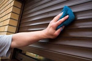 hand cleaning roller shutters with rug | exterior house cleaning