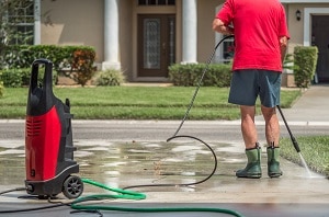Man using electric powered pressure washer to power wash residential concrete driveway | is pressure washing environmentally friendly