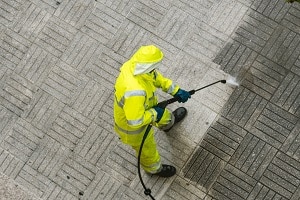 Top view of a Worker cleaning the street sidewalk with high pressure water jet | house pressure washing prices