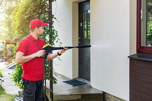 man in uniform pressure washing exterior of house | how to pressure wash a house before painting