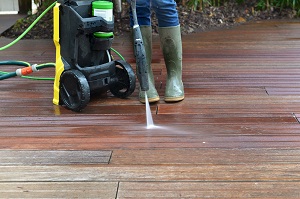 woman washing wooden terrace with high pressure water | pressure wash a wood deck