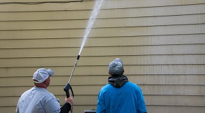 man power washing the siding and the other is watching | dealing with vinyl siding oxidation