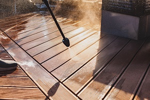 man cleaning wooden deck of terrace with a power washer | what is soft washing