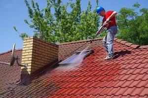 man standing on house roof pressure washing it | pressure washing for house