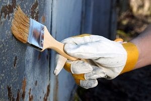 man holding brush against rusty steel surface | professional house cleaning