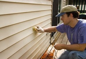 man cleaning vinyl siding with brush | house cleaning services