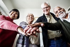 group of senior citizens putting hands together | cleaning services for retirement communities